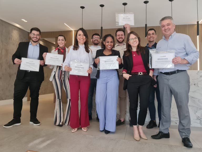 Grupo de profissionais com os certificados de conclusão do programa de formação